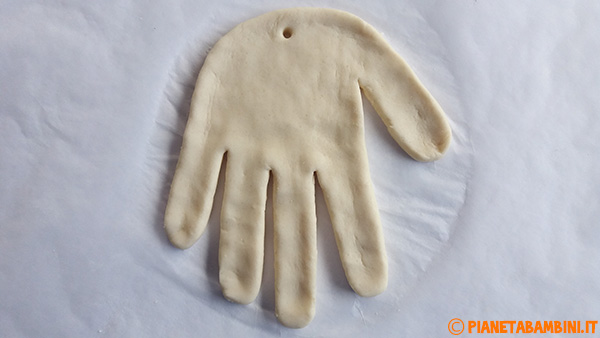Ritaglio della forma della mano in pasta di sale per creare il viso di Babbo Natale